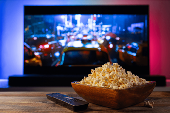 a bowl of popcorn and a remote control in front of a tv
